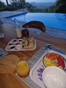 una mesa con un plato de comida y un vaso de zumo de naranja en Vista Mar y Monos en Sámara