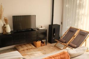 a living room with a flat screen tv and two chairs at A casa da Lomba in Lomba