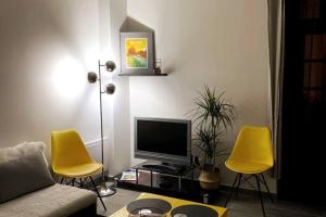 a living room with two yellow chairs and a television at « La Bicyclette » 35m2 tout équipé centre ville in Mayenne