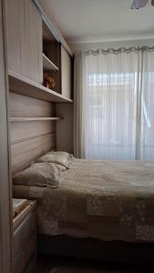 a bedroom with a bed and a window at Residencial da Leta in Garopaba
