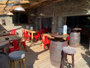 a patio with wooden tables and red chairs and tables and barrels at The Old Bath Arms in Frome