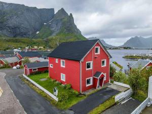 a red house with a black roof in front of a mountain at Reine Front View - Mountain & Seaview in Reine