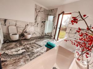 a bathroom with a toilet and a vase with red flowers at Olive garden family apartment with private pool in Sežana