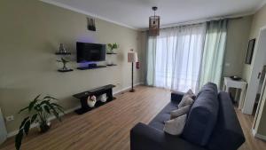 a living room with a blue couch and a tv at Villa Alta Vista in São Jorge