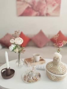 Una mesa con una vela, jarrones y flores. en ~Charmant Studio~ Agdal Mall en Rabat