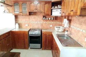 a kitchen with wooden cabinets and a stove and a sink at Kaypi Samay in Cusco