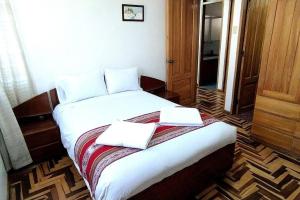 ein Schlafzimmer mit einem Bett mit zwei Handtüchern darauf in der Unterkunft Kaypi Samay in Cusco