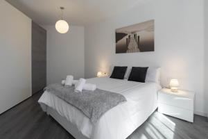 een witte slaapkamer met een groot wit bed en 2 verlichting bij Apartamento Carvajal in Málaga