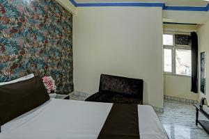 a bedroom with a bed and a chair at OYO Flagship HOTEL RAJENDRA PALACE in Kānpur