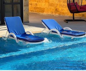due sedie blu sedute in una piscina d'acqua di AL-TARAF FARM a Umm el ‘Amad