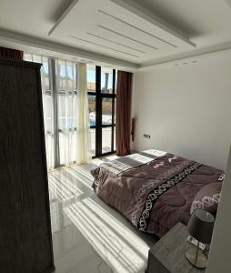 a bedroom with a large bed and a large window at AL-TARAF FARM in Umm el ‘Amad