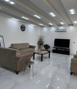 a living room with couches and a flat screen tv at AL-TARAF FARM in Umm el ‘Amad
