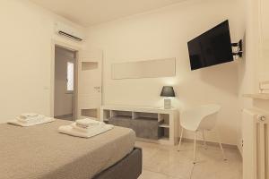 a white room with a bed and a desk and a television at GLADIUS B&B in Santa Maria Capua Vetere