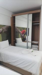 1 dormitorio con cama y espejo grande en Apto Eco Resort Capivari - CTBA, en Campina Grande do Sul