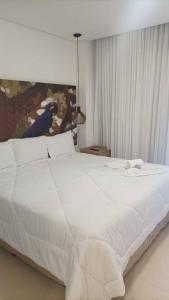 - une chambre avec un lit blanc orné d'une peinture murale dans l'établissement Apto Eco Resort Capivari - CTBA, à Campina Grande do Sul