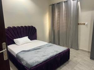 1 dormitorio con 1 cama con cabecero púrpura y ventana en Fowaalux, en Tema