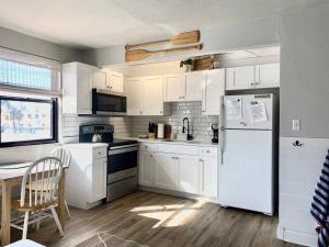 uma cozinha com armários brancos e um frigorífico branco em Ocean view balcony with heated pool em St. Pete Beach