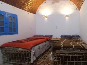 2 Betten in einem Zimmer mit einer Wand und einem Fenster in der Unterkunft Wesy Ka Guest House in Shellal