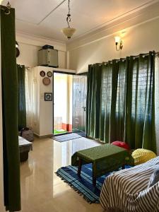 una habitación con cortinas verdes y un banco en una habitación en Cornwall for family en Madikeri