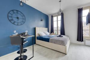 ein blaues Schlafzimmer mit einem Bett und einer Uhr an der Wand in der Unterkunft Guest loc-Le Saphir-3min château in Versailles