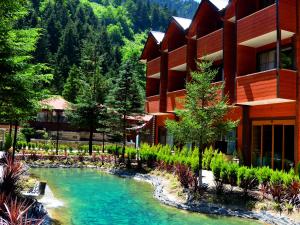 a resort with a river in front of a building at Centro Park Hotel in Uzungöl