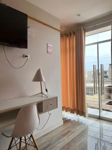 Zimmer mit einem Schreibtisch, einem TV und einem Fenster in der Unterkunft Paris Senlis Hostel Plus in Chimbote