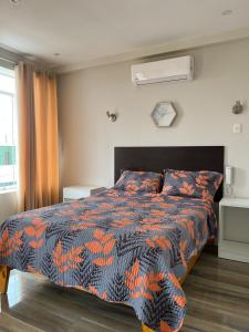 Paris Senlis Hostel Plus في شيمبوتي: غرفة نوم مع سرير مع لحاف برتقالي وأسود