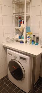 uma máquina de lavar roupa debaixo de um balcão numa cozinha em Cozy-Mozy em Estocolmo