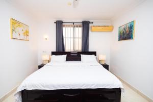 a bedroom with a large bed with white sheets at Stay Play Away Residences - 3 bed, Airport Residential, Accra in Accra