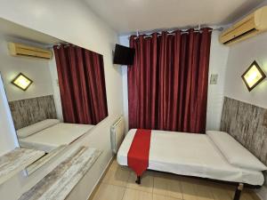 a bedroom with two beds and a red curtain at Hostal Las Vegas in Madrid