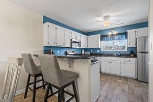 a kitchen with white cabinets and two bar stools at Little River-condo-sleeps 10 By Hostique in Little River