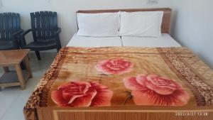 a bed with two flowers on it with two chairs at Shri Badrivishal -A mata Hotel in Badrīnāth