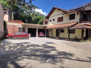 a red car parked in front of a house at Pousada Unser Haus in São Francisco de Paula