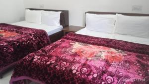 a hotel room with two beds with purple sheets at Dharmshala in Badrinath