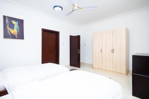2 łóżka w sypialni z białymi ścianami i drewnianymi szafkami w obiekcie Stay Play Away Residences - 3 bed, Airport Residential, Accra w Akrze