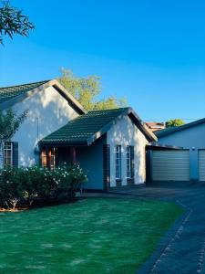 a house with a green lawn in front of it at The M-Pire Cottage in Bloemfontein