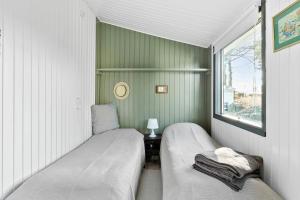 2 camas en una habitación pequeña con ventana en Traditionelles Ferienhaus direkt am Ostseestrand, en Otterup