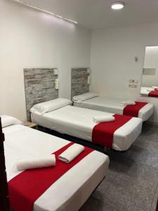 a room with four beds with red and white sheets at Hostal Las Vegas in Madrid