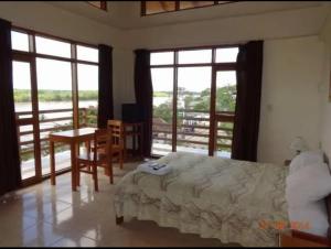 a bedroom with a bed and a table and windows at Hostal El Puerto in Yurimaguas