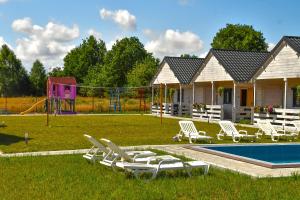 een tuin met een zwembad en stoelen en een speeltuin bij Apartamenty Biel i Zieleń in Nacmierz