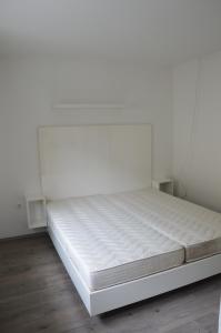 uma cama branca num quarto com uma parede branca em Haus Im Zentrum L mit 2 Schlafzimmer und garten em Szombathely