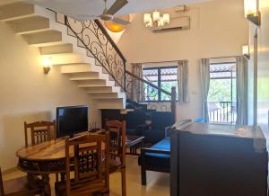 a living room with a staircase and a table and chairs at Riviera Foothills Duplex Apartment in Arpora