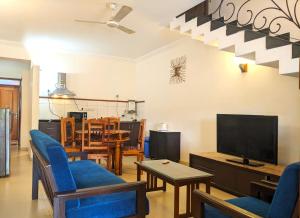 a living room with blue chairs and a flat screen tv at Riviera Foothills Duplex Apartment in Arpora