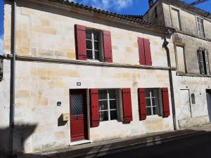 an old stone building with red shutters on it at ON LOGE A PIED ET A CHEVAL in Jonzac