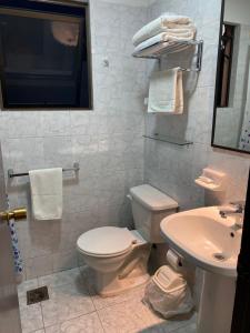 a white bathroom with a toilet and a sink at De La Costa Cabañas in La Serena