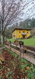 una recinzione di legno di fronte a una casa gialla di Casa mandoia a Igorre