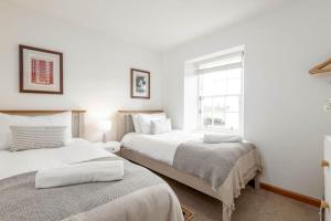 2 łóżka w pokoju z białymi ścianami i oknem w obiekcie Crail Town House - Sleeps 6 w mieście Crail