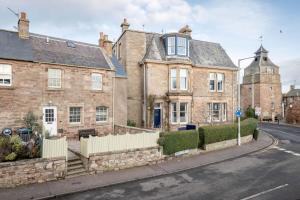 an old brick house with a white fence on a street at Crail Town House - Sleeps 6 in Crail