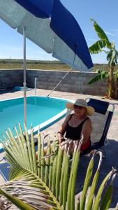 une femme assise sur une chaise près d'une piscine dans l'établissement Sobradinho Nova Torres, 