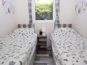 een slaapkamer met 2 bedden en een raam bij Luxury chalet on cozy family campsite. in Garderen